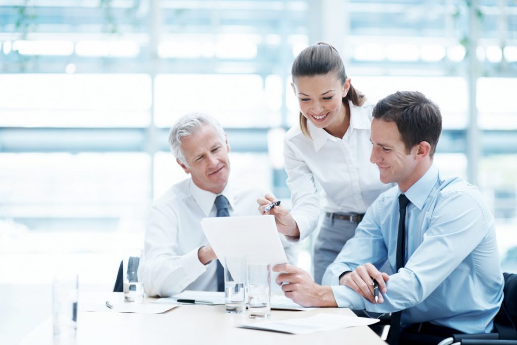 Zwei Männer und eine Frau diskutieren gemeinsam am Meeting-Tisch.